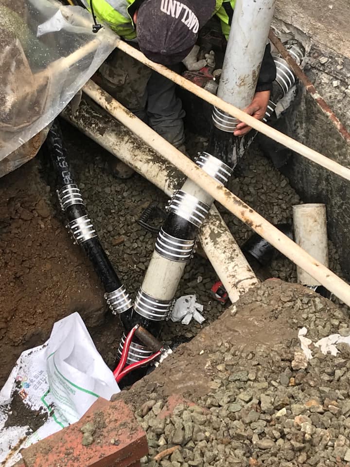 A worker underground fixing plumbing pipes